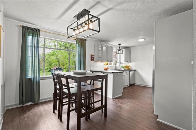 dining space with baseboards, a textured ceiling, and dark wood finished floors