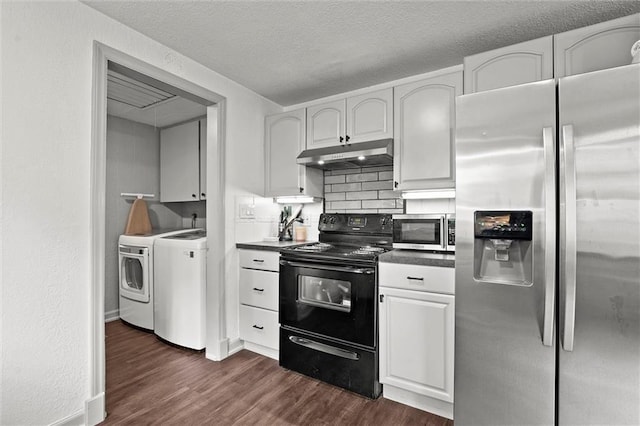 kitchen featuring washing machine and clothes dryer, dark countertops, stainless steel appliances, under cabinet range hood, and dark wood-style floors