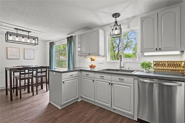 kitchen with a sink, dark countertops, a textured ceiling, and dishwasher