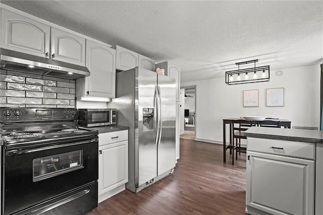 kitchen with dark countertops, a textured ceiling, stainless steel appliances, under cabinet range hood, and dark wood-style floors