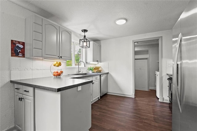 kitchen featuring dark wood-type flooring, a textured ceiling, a sink, backsplash, and stainless steel appliances