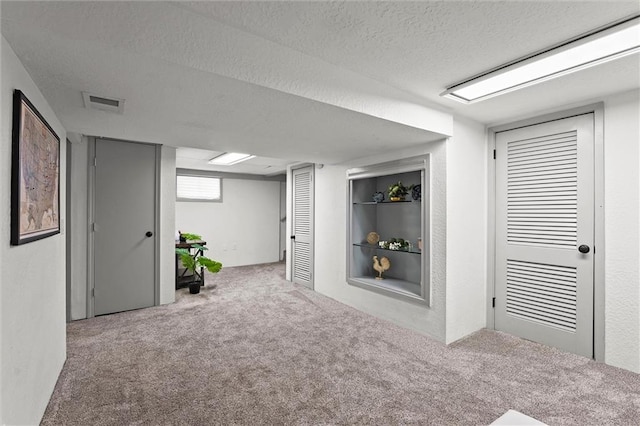basement with carpet floors, a textured ceiling, and visible vents