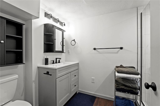 full bathroom with vanity, wood finished floors, toilet, baseboards, and a textured ceiling