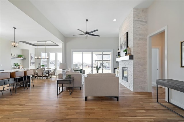 living room featuring wood finished floors, a ceiling fan, and a stone fireplace