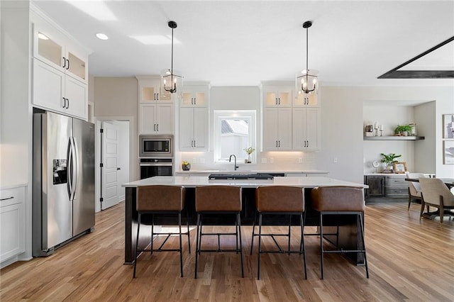 kitchen featuring light wood finished floors, white cabinetry, light countertops, appliances with stainless steel finishes, and a kitchen island