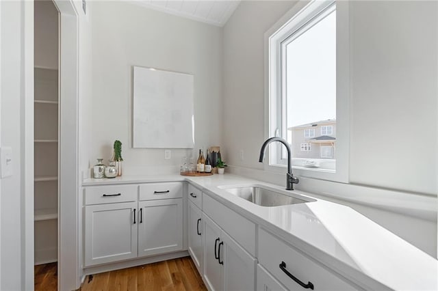 kitchen with light wood-style flooring, light countertops, white cabinets, and a sink