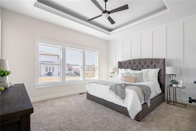 bedroom with baseboards, a tray ceiling, ceiling fan, and carpet