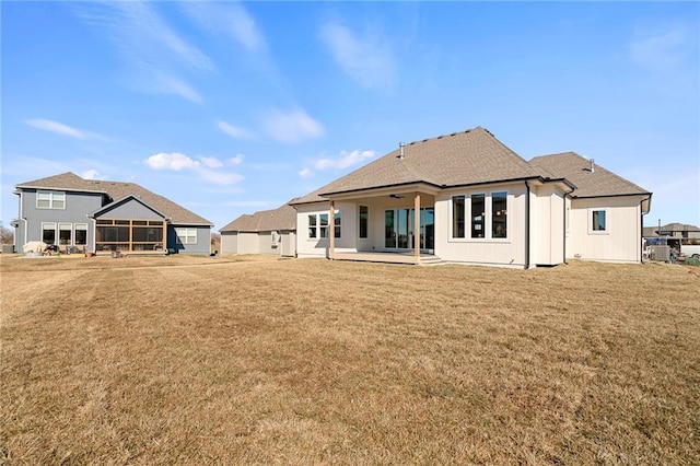 rear view of property with a yard, a sunroom, a patio area, and board and batten siding
