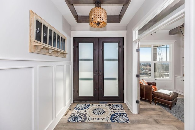 entryway with a decorative wall, a wainscoted wall, wood finished floors, and french doors