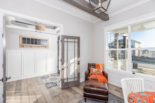 living area with light wood finished floors, ornamental molding, and a decorative wall