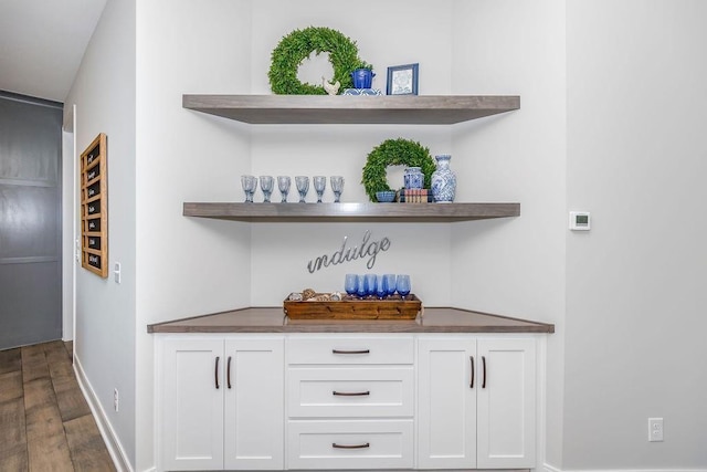 bar featuring baseboards, bar area, and wood finished floors
