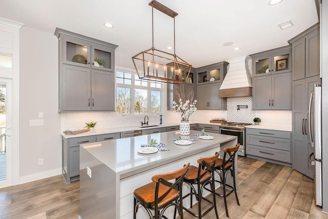 kitchen with light wood-style flooring, premium range hood, appliances with stainless steel finishes, and gray cabinetry