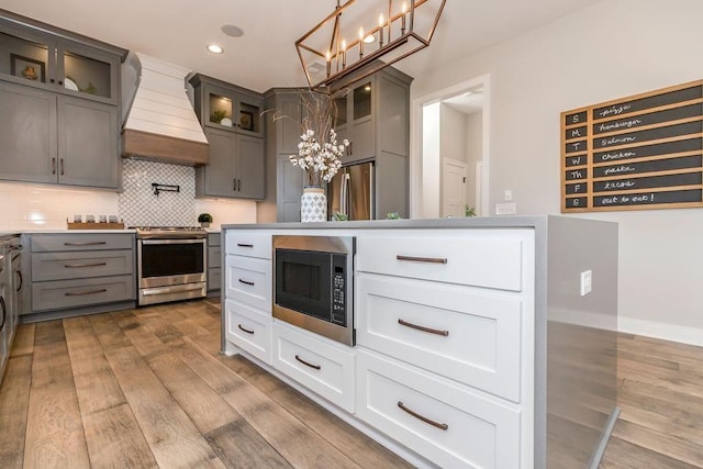 kitchen with appliances with stainless steel finishes, a chandelier, custom exhaust hood, and dark wood-style floors