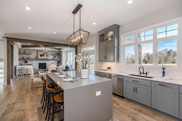 kitchen featuring a center island, a sink, dishwasher, decorative backsplash, and gray cabinetry