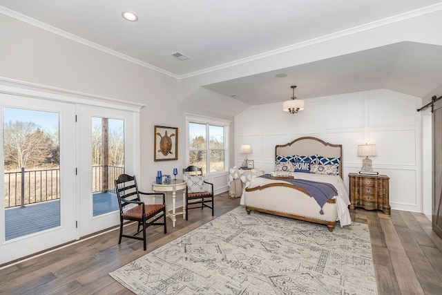 bedroom with wood finished floors, a barn door, visible vents, and access to exterior