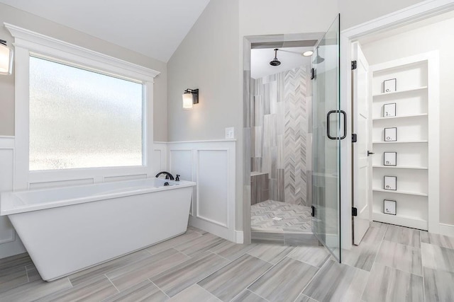bathroom with a shower stall, lofted ceiling, and a soaking tub