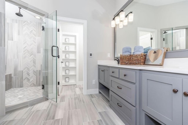 bathroom featuring double vanity, a stall shower, and a sink