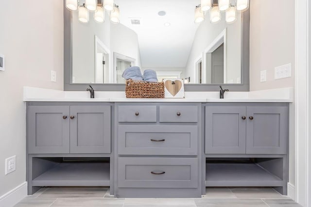 bathroom with baseboards, visible vents, double vanity, and a sink