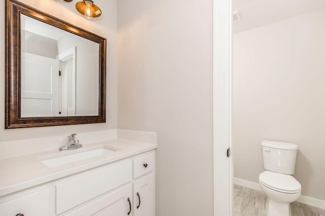 bathroom with toilet, baseboards, and vanity