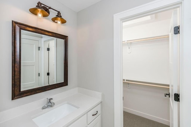 bathroom featuring vanity, a spacious closet, and baseboards