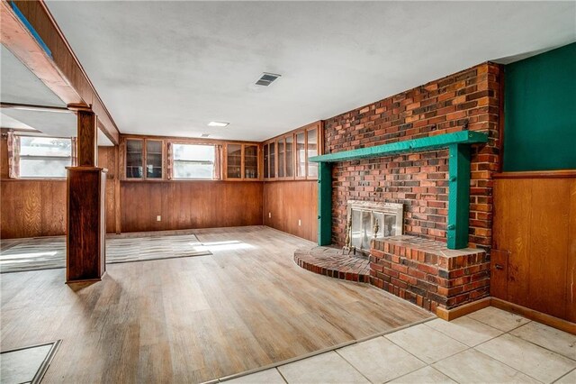 2806 S Whitney Ave, Independence, MO 64057 - unfurnished living room featuring wooden walls, a fireplace, and wood finished floors