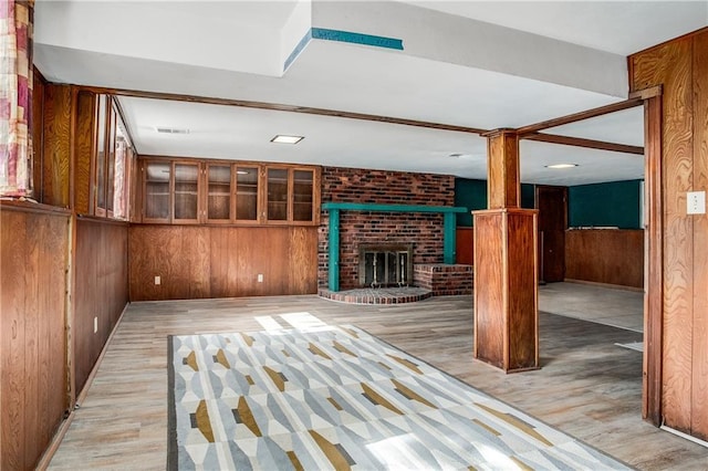 2806 S Whitney Ave, Independence, MO 64057 - unfurnished living room featuring wooden walls, decorative columns, a fireplace, and light wood-type flooring