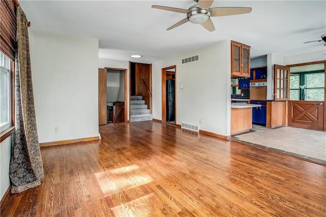 2806 S Whitney Ave, Independence, MO 64057 - unfurnished living room with a ceiling fan, light wood-type flooring, stairs, and baseboards
