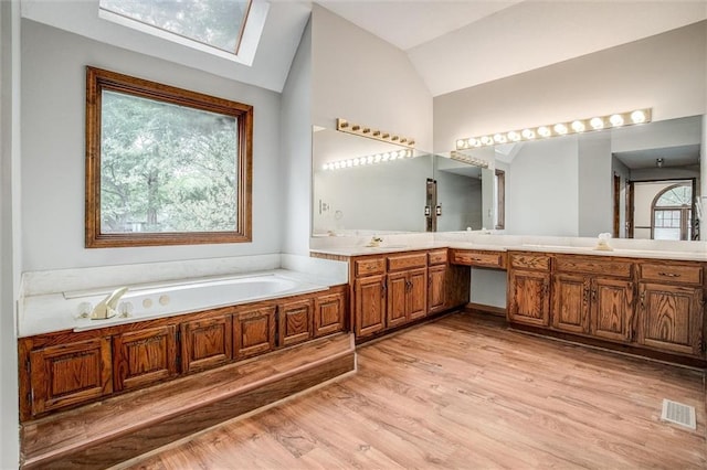 4008 NW 75th St, Kansas City, MO 64151 - full bathroom featuring a garden tub, lofted ceiling, wood finished floors, a skylight, and double vanity