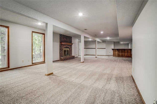 4008 NW 75th St, Kansas City, MO 64151 - basement with carpet flooring, a fireplace, recessed lighting, a textured ceiling, and baseboards