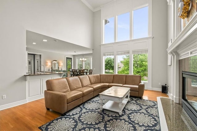 2704 SW Gray Ln, Lees Summit, MO 64081 - living room with a towering ceiling, a fireplace, wood finished floors, baseboards, and a chandelier