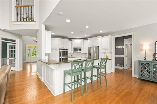 2704 SW Gray Ln, Lees Summit, MO 64081 - kitchen featuring stainless steel appliances, a kitchen breakfast bar, white cabinetry, light wood finished floors, and recessed lighting