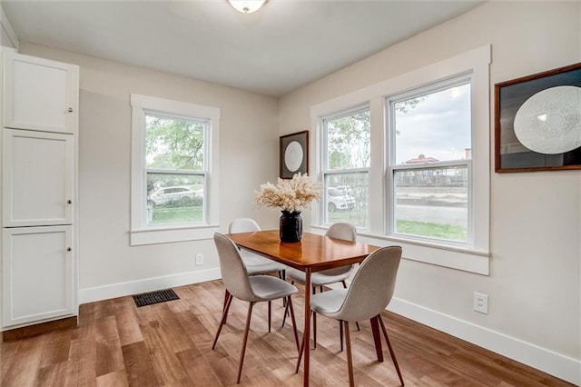 dining space with healthy amount of natural light, baseboards, and wood finished floors
