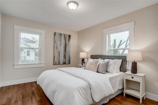 bedroom featuring multiple windows, baseboards, and wood finished floors