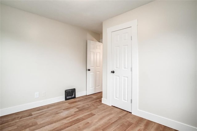 spare room with baseboards and light wood-type flooring