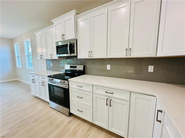 kitchen featuring light wood-type flooring, light countertops, white cabinetry, and appliances with stainless steel finishes