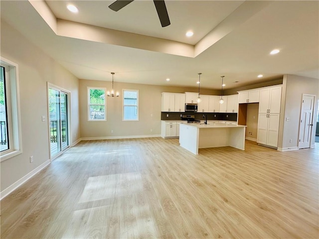 kitchen with light wood-type flooring, open floor plan, appliances with stainless steel finishes, and ceiling fan with notable chandelier