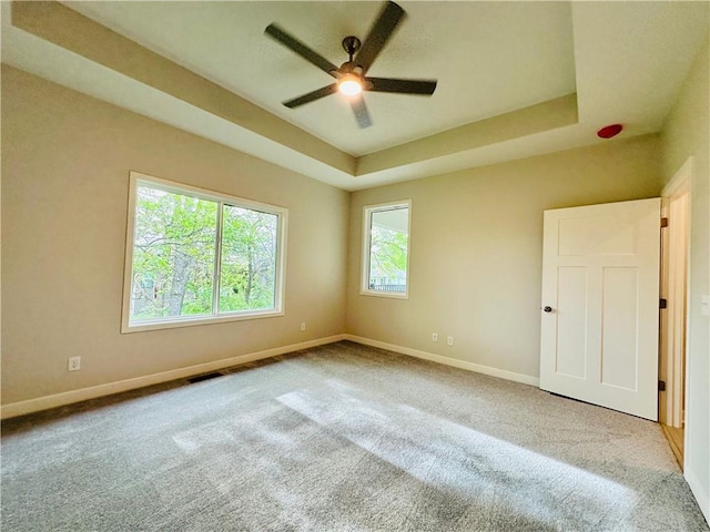 unfurnished room featuring baseboards, a ceiling fan, carpet, and a raised ceiling
