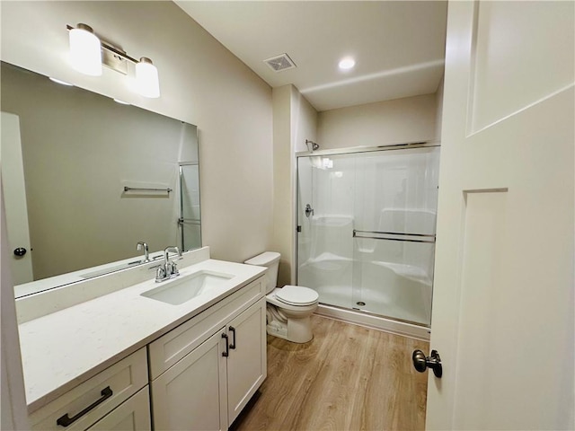 bathroom with visible vents, a stall shower, wood finished floors, vanity, and toilet