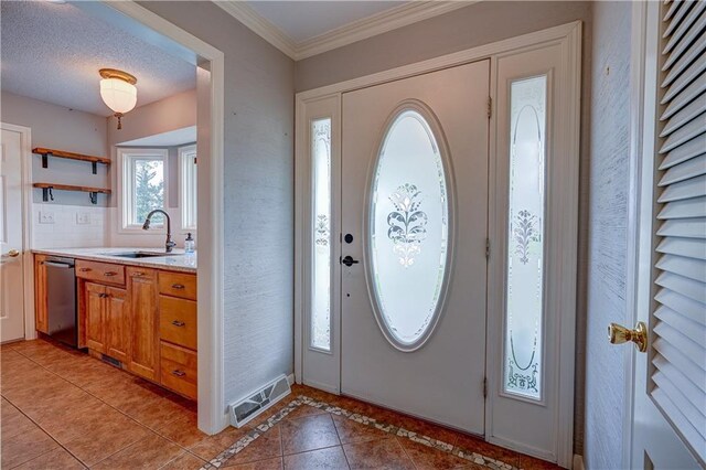 foyer featuring baseboards, visible vents, ornamental molding, and light tile patterned floors