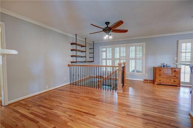 interior space featuring baseboards, ceiling fan, ornamental molding, and wood finished floors