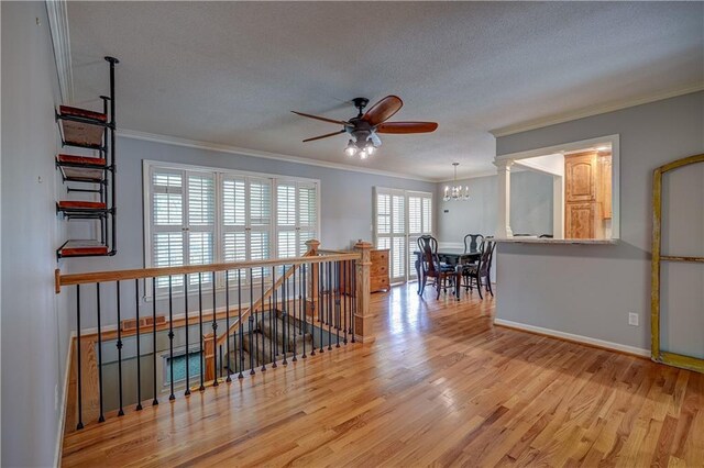 interior space with ornamental molding, a textured ceiling, ceiling fan with notable chandelier, and wood finished floors