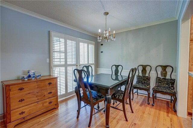 dining area with an inviting chandelier, ornamental molding, a textured ceiling, and light wood-type flooring