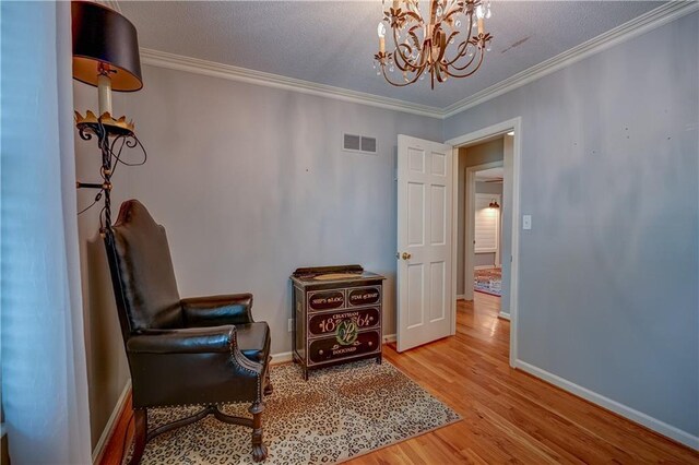 sitting room featuring visible vents, crown molding, wood finished floors, baseboards, and an inviting chandelier