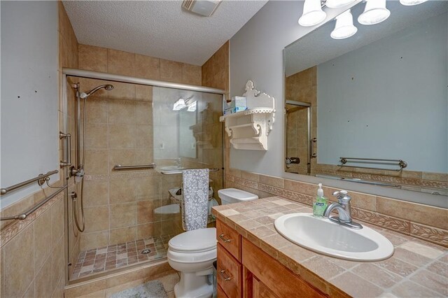 bathroom with vanity, a textured ceiling, a stall shower, and toilet