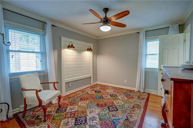 sitting room featuring crown molding, a ceiling fan, light wood finished floors, and a textured ceiling