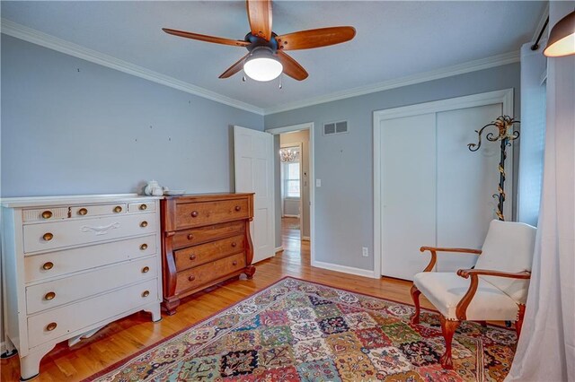 living area featuring ceiling fan, visible vents, baseboards, light wood-style floors, and ornamental molding
