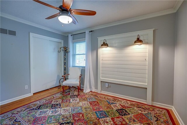 unfurnished room featuring visible vents, crown molding, wood finished floors, baseboards, and ceiling fan