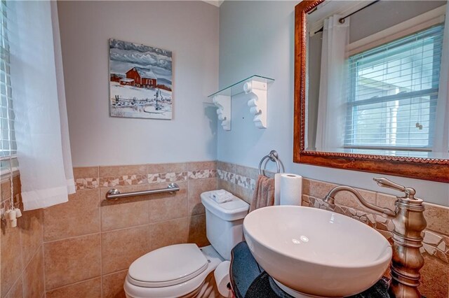 bathroom featuring plenty of natural light, a sink, toilet, and tile walls