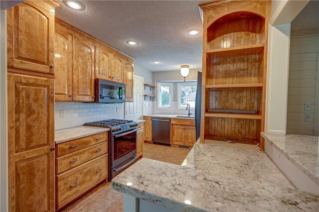 kitchen featuring a textured ceiling, open shelves, appliances with stainless steel finishes, and decorative backsplash