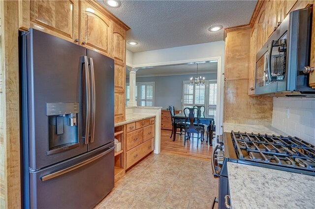 kitchen featuring backsplash, a textured ceiling, stainless steel appliances, ornate columns, and light tile patterned flooring